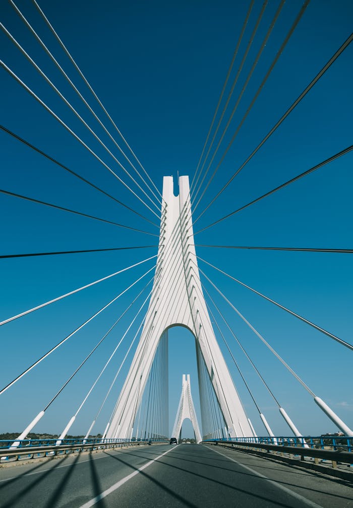 services-05 Explore the stunning architecture of a Portuguese suspension bridge under a clear blue sky.