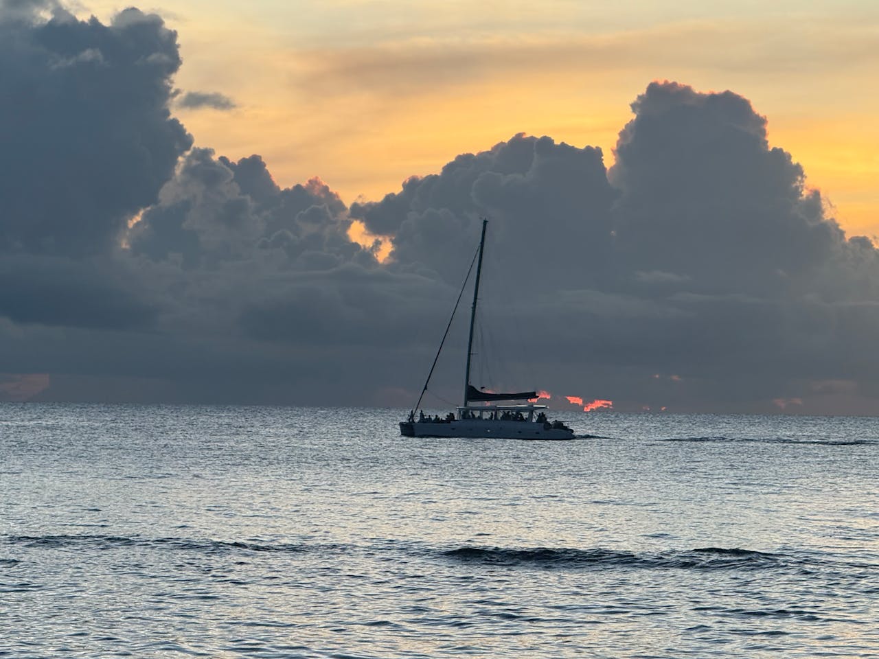 services-06 A sailboat drifts across the ocean during a breathtaking sunset with dramatic clouds.